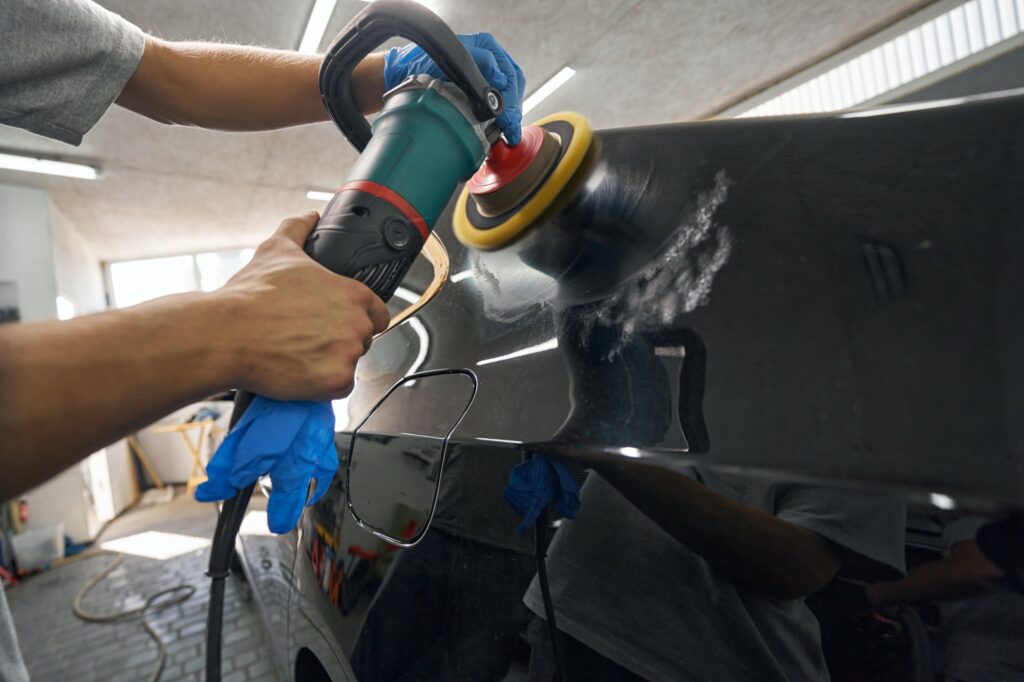 Car detailing studio worker polishing car paint and removing stratches